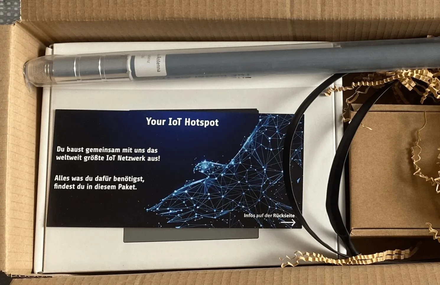 An IoT hotspot in its shipping box, next to a card reading “Your IoT Hotspot”